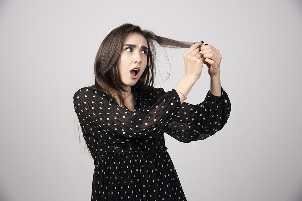 donna che si guarda i capelli e si preoccupa per la caduta continuata di capelli