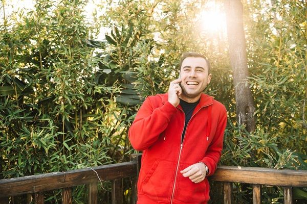 Uomo allegro che parla allo smartphone nel parco