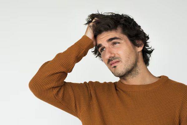 uomo bianco in maglione casual con mano sulla testa e volto preoccupato