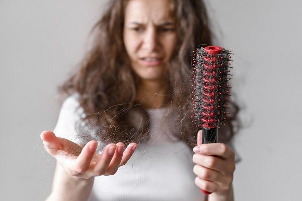 donna che guarda stupita la caduta dei suoi capelli