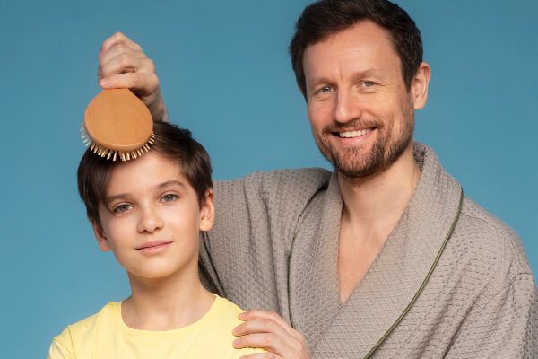 uomo adulto sorridente che spazzola i capelli del bambino