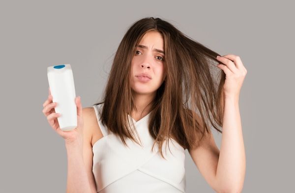 Donna con una bottiglia di shampoo in mano con un grave problema di perdita di capelli per lo shampoo di cura della salute.