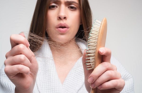 Donna triste che guarda i capelli danneggiati, problema di perdita di capelli. Studio isolato, spazio di copia per ritratto.