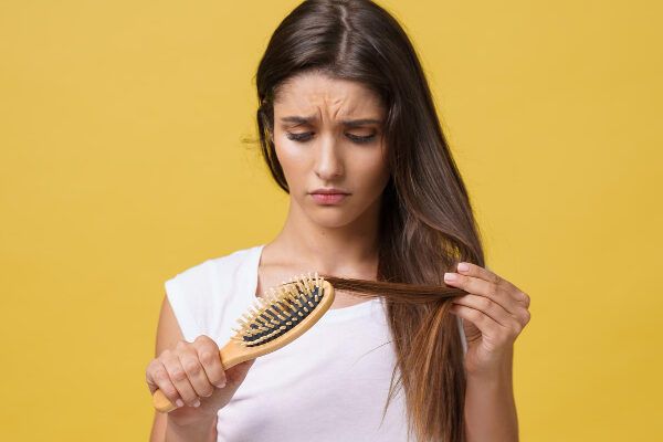 Ragazza che si pettina i capelli con una faccia frustrata.