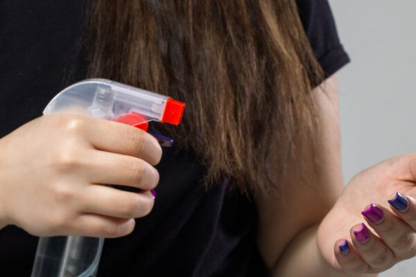 Donna che si spruzza la mano - Donna che applica un prodotto sui capelli.
