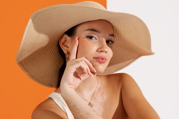 Modella in posa con un cappello - Quale crema solare fa bene?