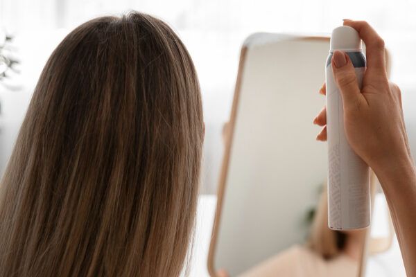 Ragazza che si spruzza i capelli con lo spray - Quale crema solare fa bene?