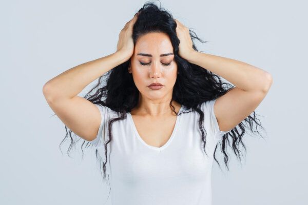 Donna che si tiene la testa con espressione preoccupata - Angioma del cuoio capelluto.
