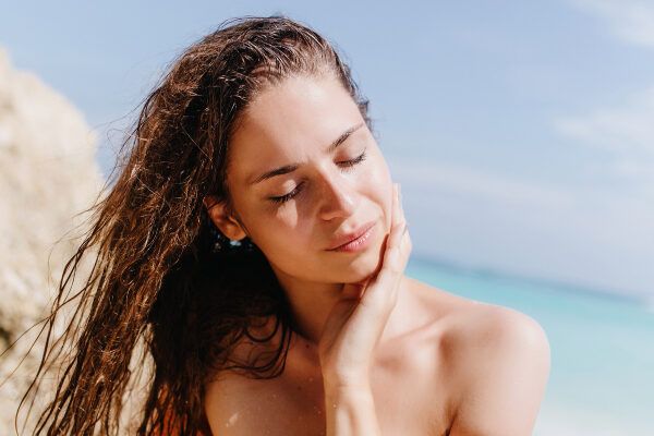 Donna che prende il sole sulla riva della spiaggia - Quale crema solare fa bene?