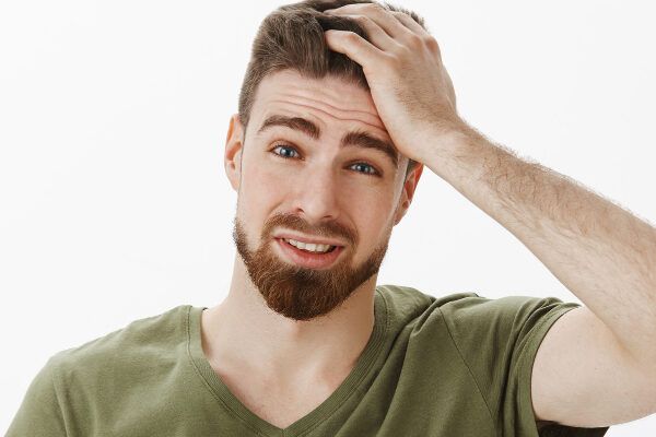 Giovane ragazzo che si strofina il cranio - Giovane ragazzo che si accarezza la testa con dubbio o preoccupazione.