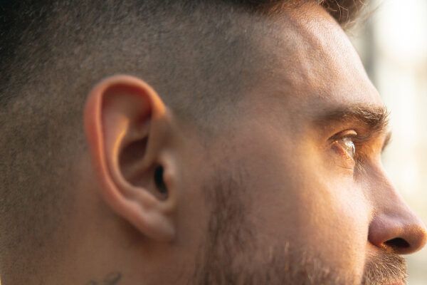 Uomo con la testa rasata e gli occhi chiari che guardano l'orizzonte.