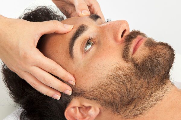 Uomo barbuto in una spa che riceve un massaggio sul cuoio capelluto.