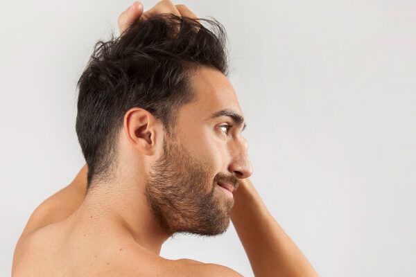 Uomo modello in posa sorridente mentre si pettina i capelli - Fase crescita dei capelli