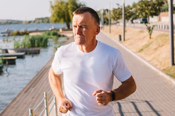Senior adulto che fa jogging in flanella bianca mentre prende il sole - Estate e calvizie