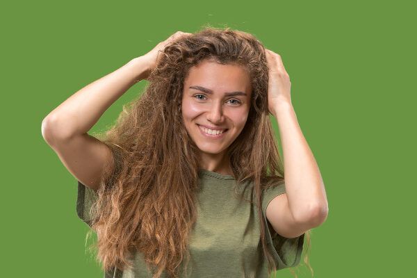 Giovane donna con lineamenti fini bionda con capelli danneggiati sorridente - Riparare i capelli danneggiati.