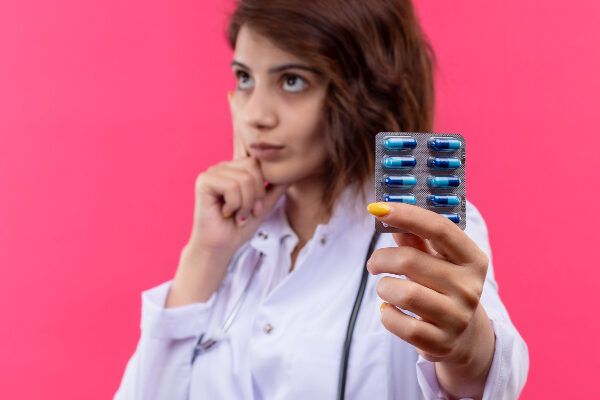 Giovane dottoressa in camice bianco che tiene blister di pillole nelle sue mani - Spironolattone per l'alopecia