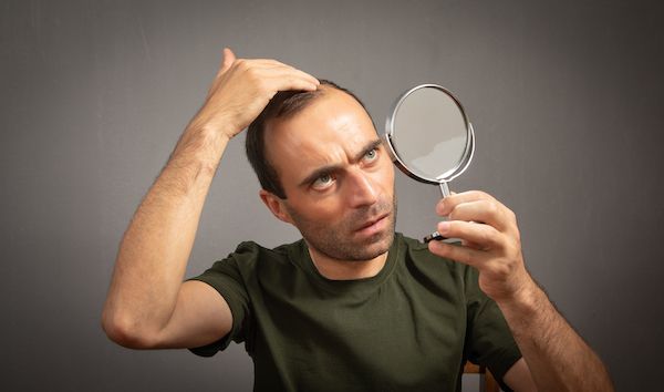 uomo che si guarda allo specchio caduta di capelli