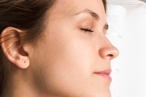 Donna con un viso pulito che posa di profilo e in modo rilassato mentre è sottoposta a terapia - L'irsutismo ormonale.