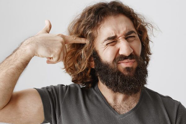 Uomo dai capelli eccessivi che punta i capelli con un'espressione confusa e stressata - Cos'è l'ipertricosi?