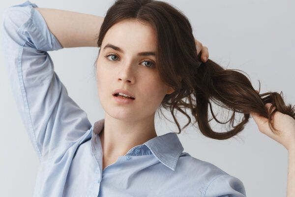 Ritratto di bella giovane donna che si scompiglia i capelli con le mani.