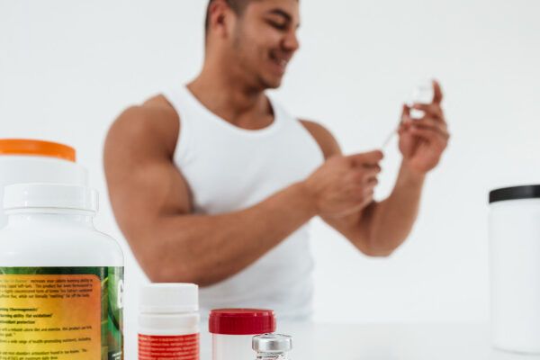 Uomo sorridente dalla carnagione scura con prodotti nutrizionali in mano - Frullati proteici e calvizie.