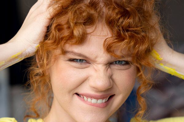 Giovane con gli occhi chiari e i capelli ricci rossastri che si morde maliziosamente il labbro mentre guarda la telecamera - Slugging provoca la caduta.