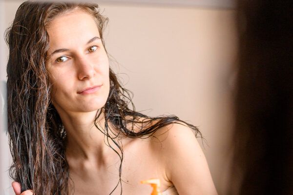 Donna con i capelli bagnati che si guarda allo specchio quando esce dalla doccia.