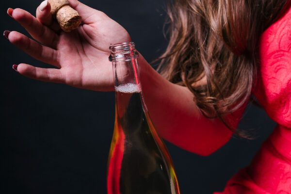 Donna che stappa una bottiglia di alcol frizzante.