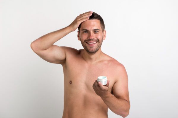 Ragazzo dai capelli corti che sorride prendendo il gel con le mani per applicarlo.
