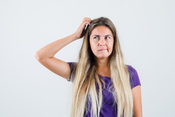 Ragazza con lunghi capelli tinti che guarda pensieroso con un'espressione di dubbio.