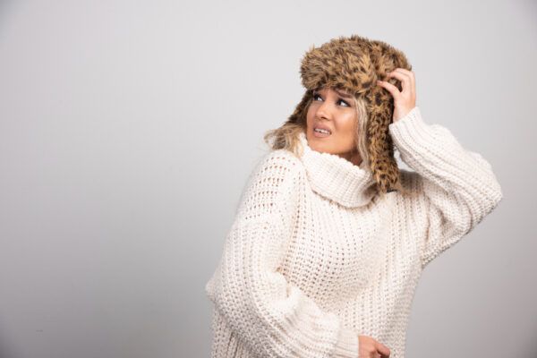 Bella giovane donna in abito invernale e accessori che guarda di lato con espressione scontenta.