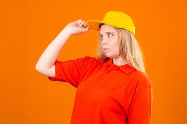 Ragazza bionda con camicia rossa in posa davanti alla telecamera mentre indossa un berretto.
