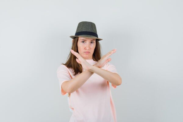 Ragazza in posa davanti alla telecamera mentre fa una X di insoddisfazione con le sue braccia.