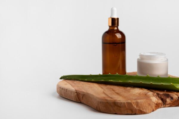 Integratori per migliorare la salute dei capelli. Contenitore di olio, foglia di aloe vera e creme utili.