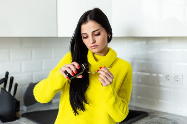 Ragazza con un maglione giallo che serve sciroppo liquido su un tavolo con una bottiglia in mano.