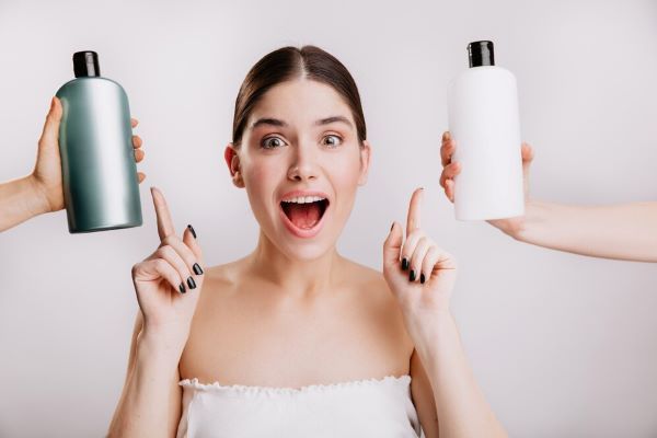 Ragazza sorridente mentre indica due bottiglie di shampoo