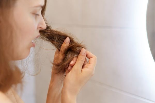 Ragazza che ispeziona una ciocca di capelli spaventata