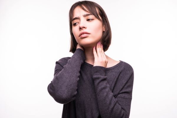 Ragazza in posa per la macchina fotografica con le mani intorno al collo
