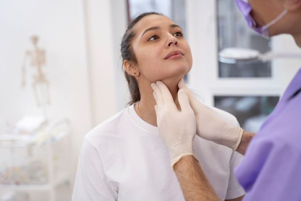 Medico che controlla il collo di un paziente