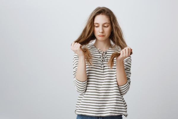 Ragazza triste che si guarda i capelli