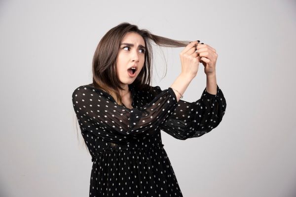 Ragazza sorpresa dalla ciocca dei suoi capelli. A volte ci chiediamo: diventerò calva?