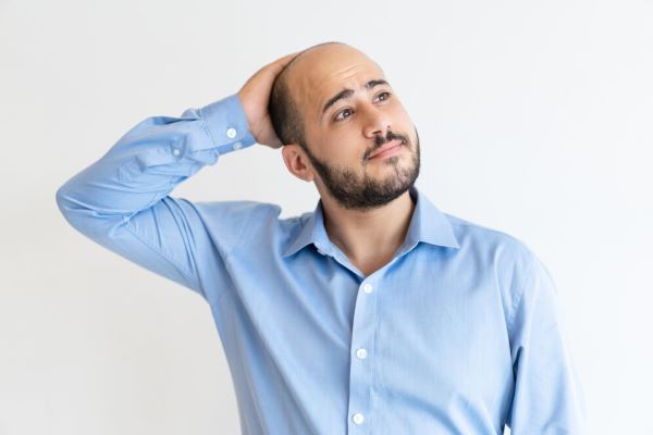 Uomo calvo che si gratta la testa
