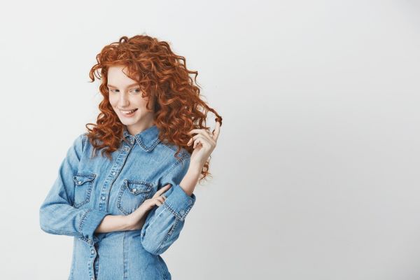Ragazza con i capelli rossi ricci che sorride