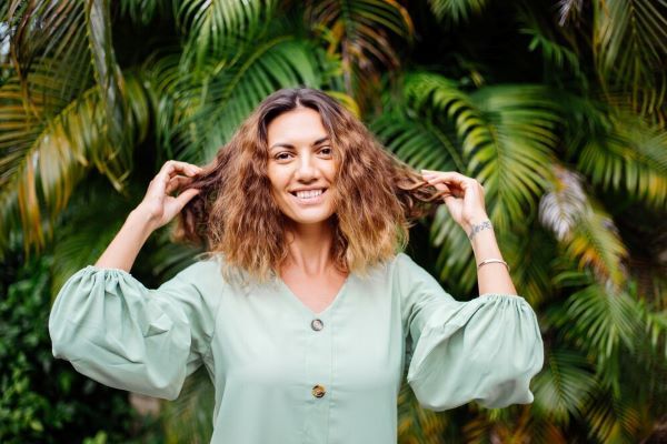 Ragazza sorridente con piante sullo sfondo