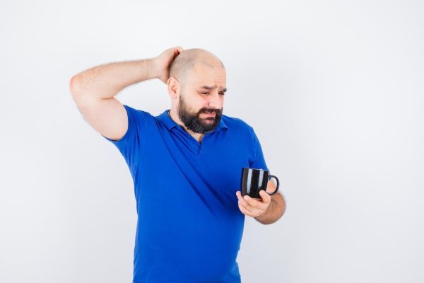 Il giovane si gratta la testa con la camicia blu.