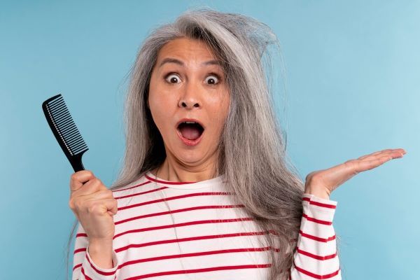 Signora anziana che si pettina i capelli arruffati