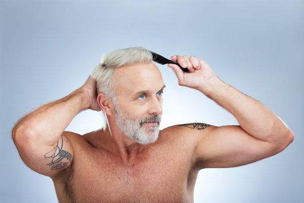 Uomo maturo che spazzola i capelli come trattamento per la salute del cuoio capelluto con un pettine su