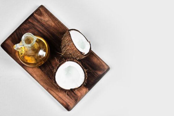 Pezzi di cocco naturale su una tavola di legno con un barattolo di olio.