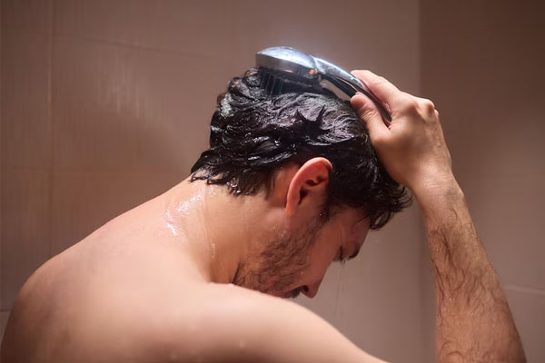 uomo girato di spalle che si lava i capelli