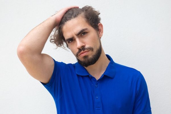 Ragazzo attraente pensoso che tocca la testa